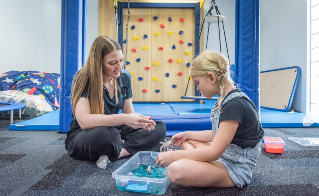 Child playing with sensory box with paediatric OT